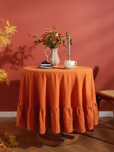 Detail van oranje katoenen tafelkleed met elegante ruches aan de zoom en textuur