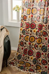 Detail of bohemian floral cotton linen curtain with vintage prints and white fringe trim