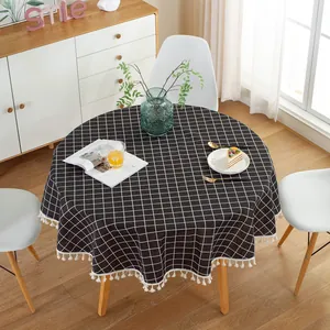 Close-up of a round black and white checkered tablecloth featuring fine white tassel edges