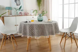 Close-up of grey plaid round tablecloth featuring elegant white tassel fringe details