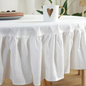 Detail shot of white ruffled edge tablecloth showing soft fabric texture and drape