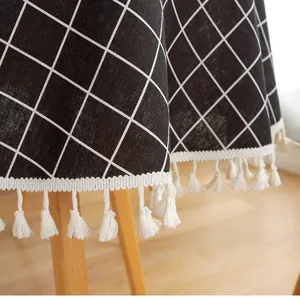 Close-up of black and white checkered linen tablecloth with decorative white fringe tassels