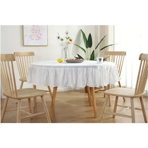 Detail of white round tablecloth with layered ruffle edges on a wooden table