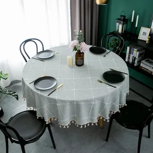 Close-up of grey-blue checkered round tablecloth with elegant white tassel fringe