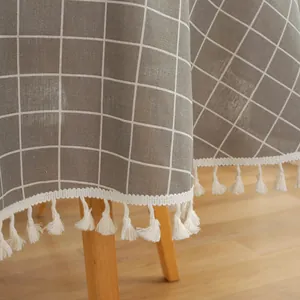 Macro detail of Nordic plaid tablecloth with elegant white cotton tassels and gray texture