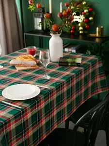 Gedetailleerde textuur van rood-groen geblokt kersttafelkleed op een houten tafel