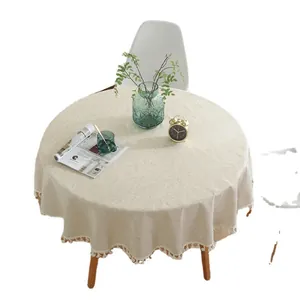 Nappe ronde beige de style nordique avec pompons et franges sur une table en bois