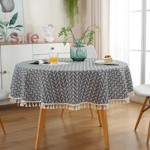 Detailed view of grey herringbone round tablecloth featuring elegant white tassel fringe edges