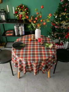 Makroaufnahme einer runden Karo-Tischdecke mit festlicher Weihnachtsdeko und warmem Licht