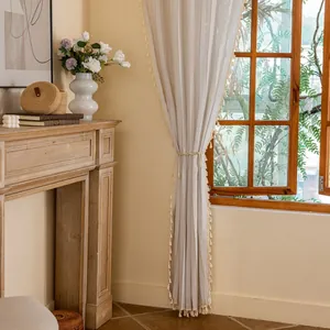 Detail of linen stripe curtain with boho tassels tied by woven rope in a warm room