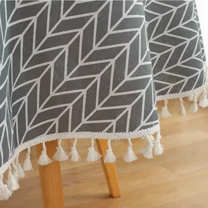 Detail of grey geometric arrow pattern linen tablecloth with decorative white tassels
