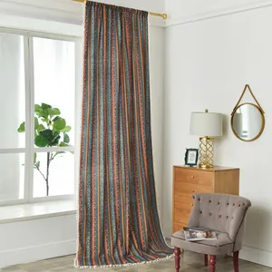 Detail of bohemian cotton linen curtain with colorful stripes and white pom-pom tassels