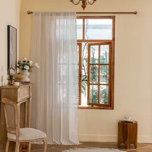 Detail of cream-white striped sheer curtain with tassel edges and rod pocket design