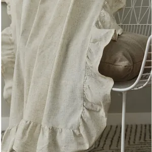 Minimalist beige linen curtain with ruffled edges draped over a white chair in a modern room