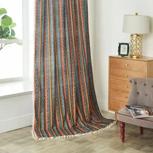 Detail of colorful bohemian striped curtains with white pom-pom fringe and cotton linen texture