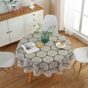 Detail of grey-green round tablecloth with white mandala pattern and fringe tassels