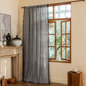 Detail of gray striped cotton linen curtain with black tassel edges and semi-sheer fabric
