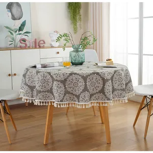 Macro detail of round grey tablecloth with white mandala floral prints and tassel fringe