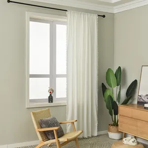 Detail of cream white curtain with delicate pom-pom fringe hanging on a rod