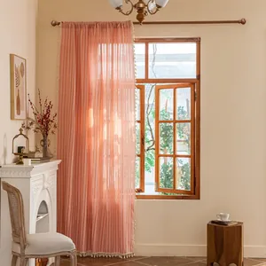 Close-up of coral semi-blackout curtain with vertical stripes and boho tassel trim