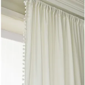 Minimalist white blackout curtain with pom-pom trim and elegant drapery hooks