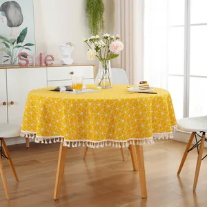 Macro detail of yellow sunflower tablecloth featuring white geometric patterns and tassel edges
