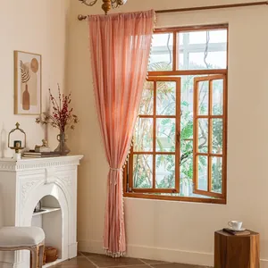 Detail of pink cotton linen curtain with white tassels and bohemian woven rope tie