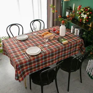 Detail van rood geruit feestelijk tafelkleed met kerstkrans en tafeldecoraties