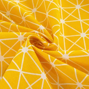Detail of yellow cotton tablecloth featuring white geometric triangle patterns and fabric texture