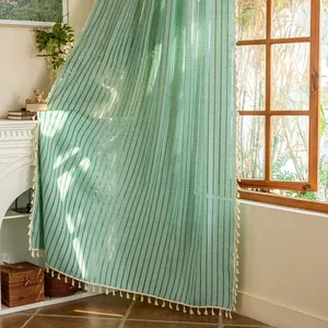 Detail showing green striped curtains with decorative cream fringe in sunlight