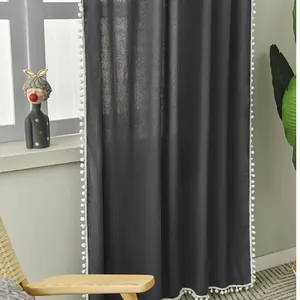 Detail of dark grey textured curtain featuring white pom-pom trim and fabric texture