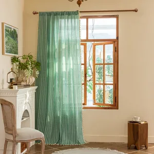 Detail of mint green sheer curtain with vertical texture and cream tassel fringe