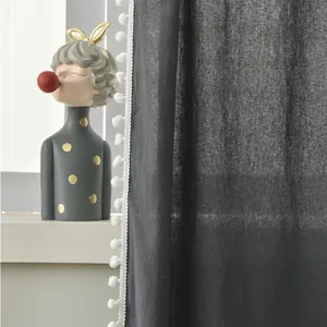 Detail of dark grey sheer curtain fabric featuring white decorative pom-pom trim edges