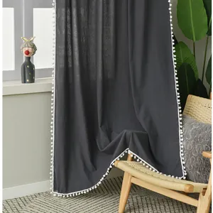 Detailed view of dark grey blackout curtain with decorative white pompom fringe trim