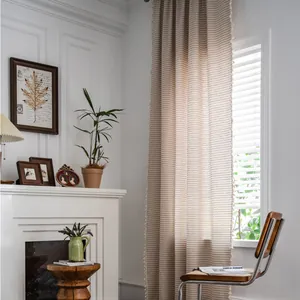 Detail of linen stripe curtain with decorative pom-pom fringe and rustic texture