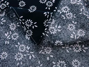 Macro detail of navy blue batik style floral fabric with white daisy patterns and fine stitching