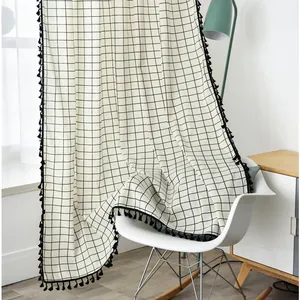 Close-up of gray and white geometric linen curtain with decorative black tassels