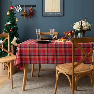 Detailweergave van het rode geruite kersttafelkleed op een houten tafel met decor