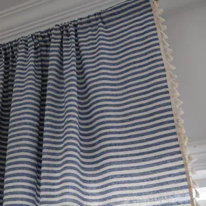 Detail of blue and white striped cotton linen curtain with decorative fringe edge