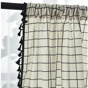 Detail of grey geometric linen curtain featuring black tassel trim and rod pocket header