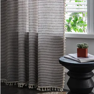 Detail of coffee and white striped linen curtain with beige tassel trim on windowsill
