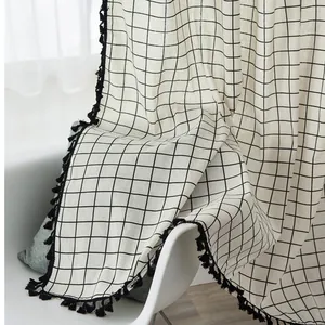Close-up of gray and white geometric cotton linen curtain with black tassel edge trim