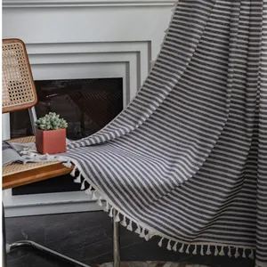 Linen boho curtain with grey stripes and white tassels on vintage chair for home decor