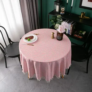 Detailed close-up of pink checkered round tablecloth with elegant fringe trim edges