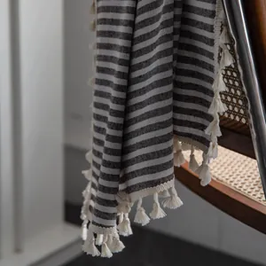 Close-up of striped cotton linen curtain fabric with white decorative tassels on edges