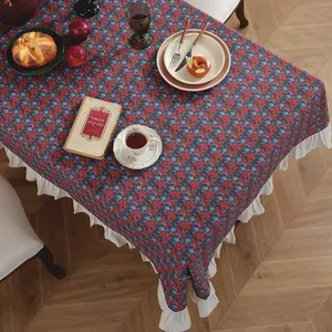 Detailed view of red floral cotton linen tablecloth with elegant white ruffled edges