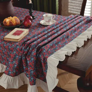 Vintage floral tablecloth with ruffled edges on a dark wood table in a cozy setup