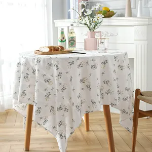 Detail of white cotton linen round tablecloth with yellow floral embroidery and wavy edge