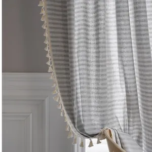 Detail of grey striped linen curtain featuring delicate cream tassel fringe edging