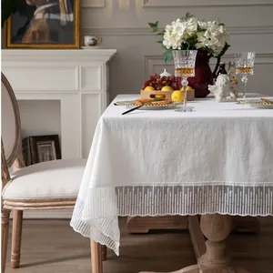 Detail van wit tafelkleed met fijn kanten randen en een elegante stoffen textuur